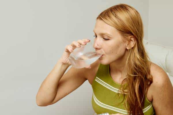 Person holding a glass of water while reading Mounjaro guidance